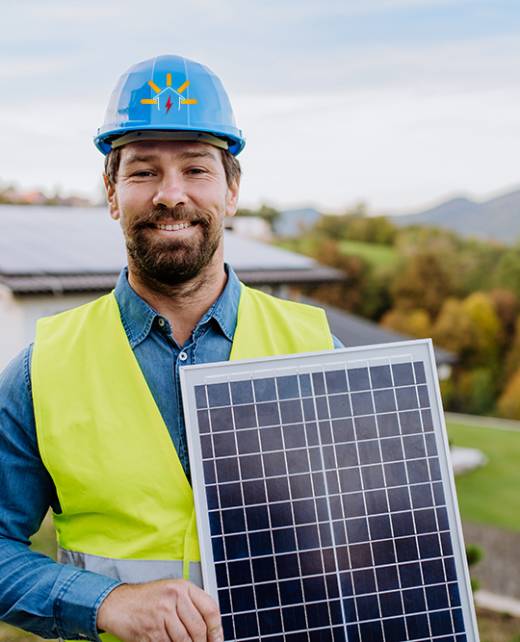 A smiling handyman solar installer carrying solar module while installing solar panel system on house.